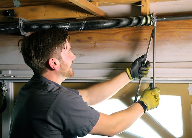 Technician making a precise garage door spring adjustment